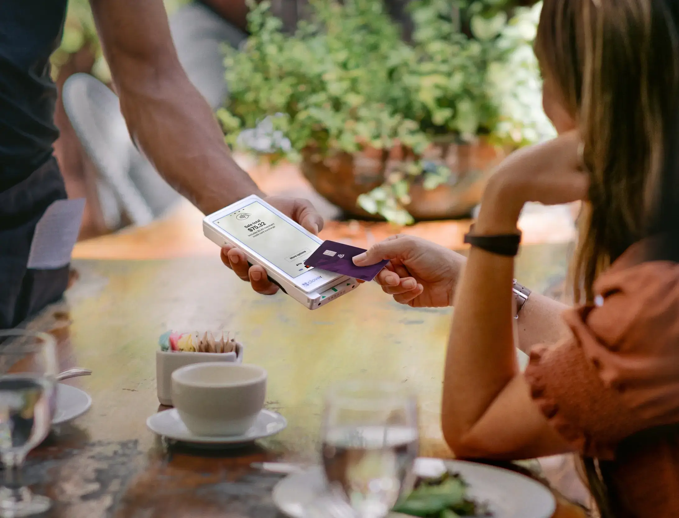 Woman paying with card on portable machine in cafe.