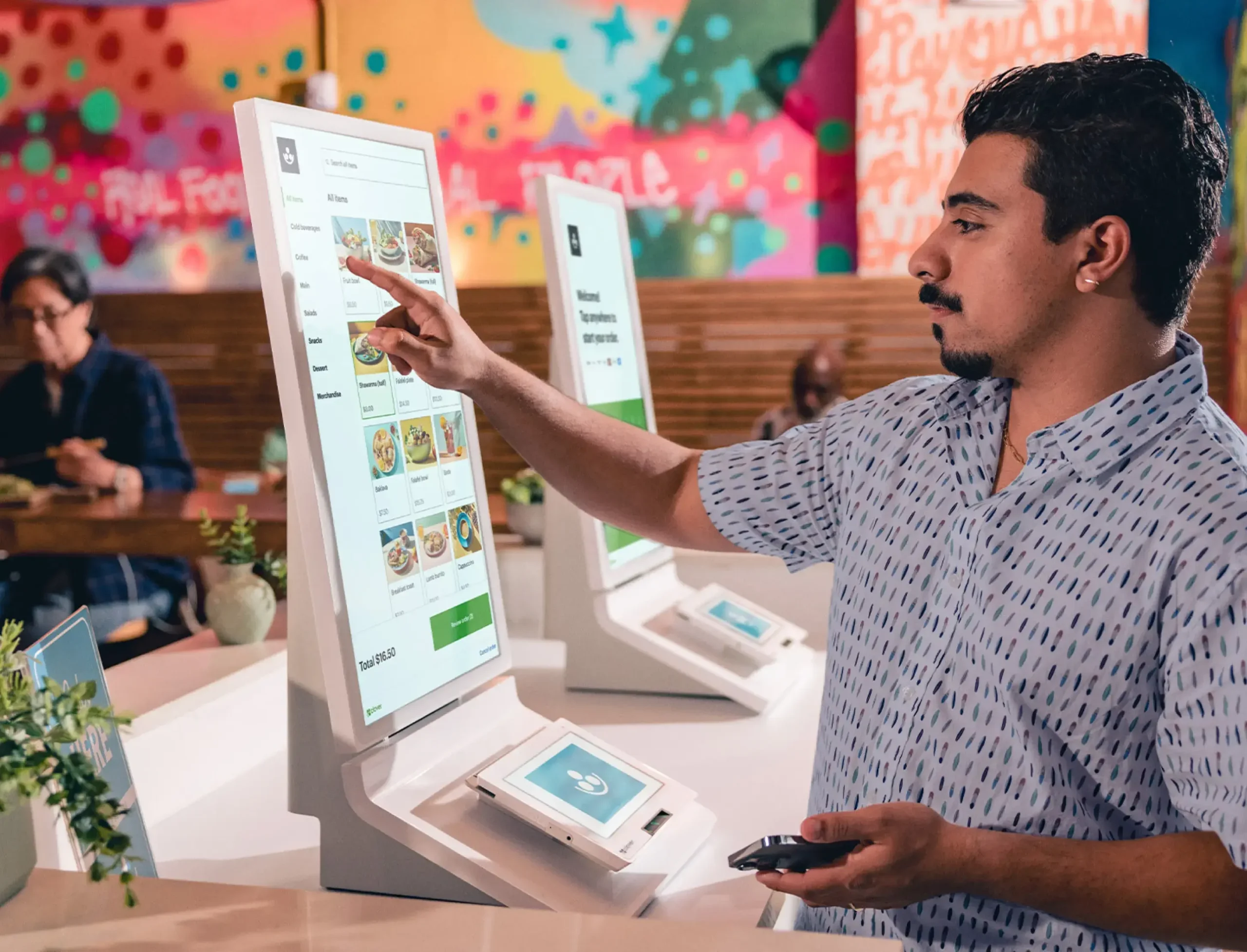 Man using self-ordering kiosk in restaurant.